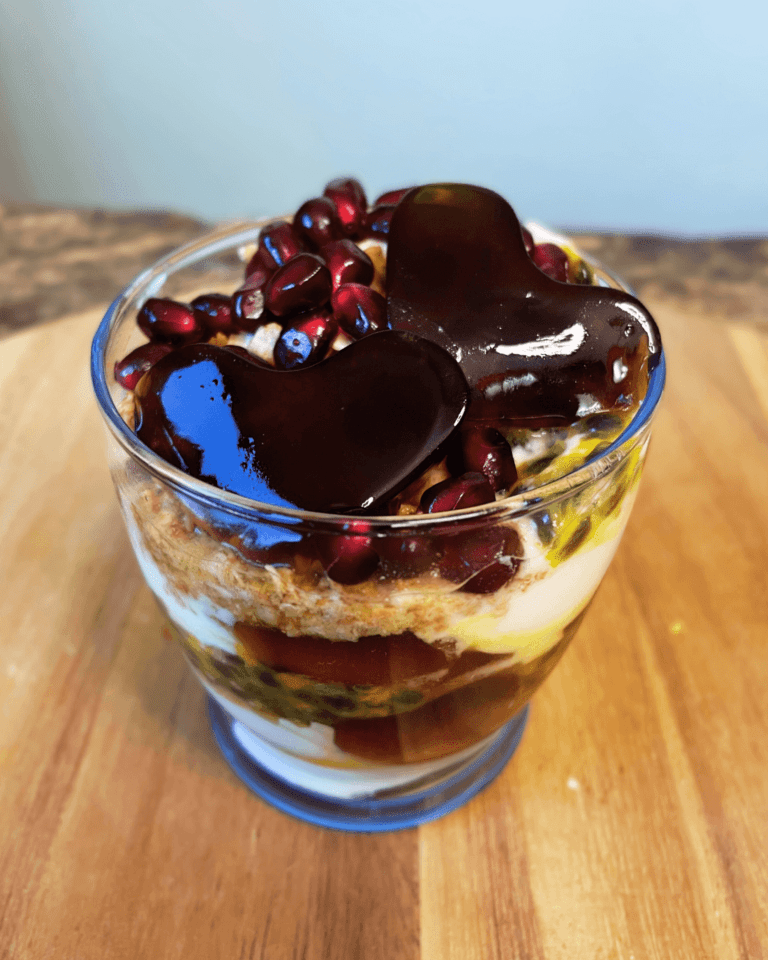 HeySweet Cranberry Chia Seed Jelly Yogurt Parfait in a glass, layered with granola, Greek yogurt, passion fruit, pomegranate seeds, and heart-shaped jelly cubes.